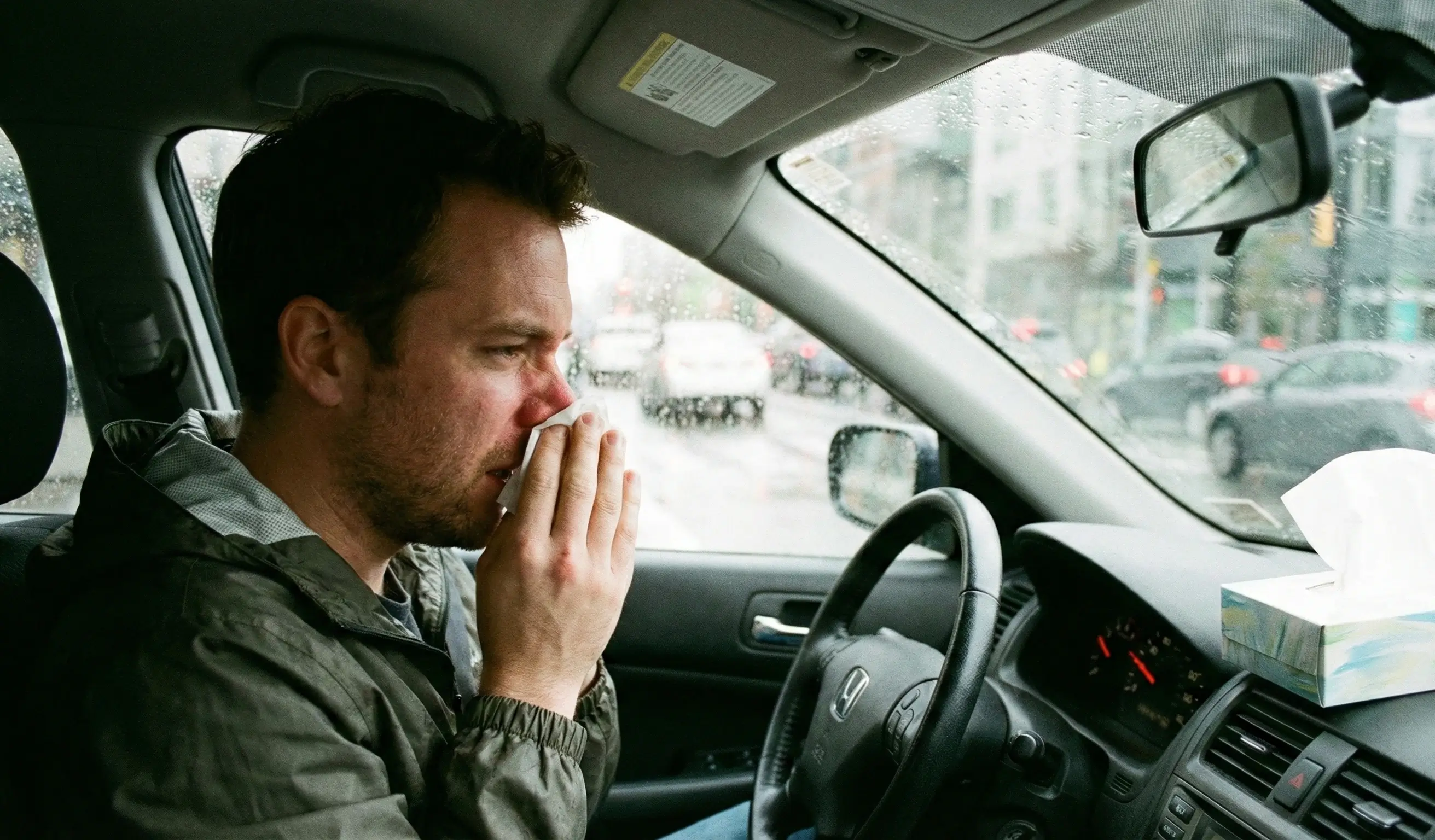 Homme avec rhinite se mouchant en conduisant dans les embouteillages