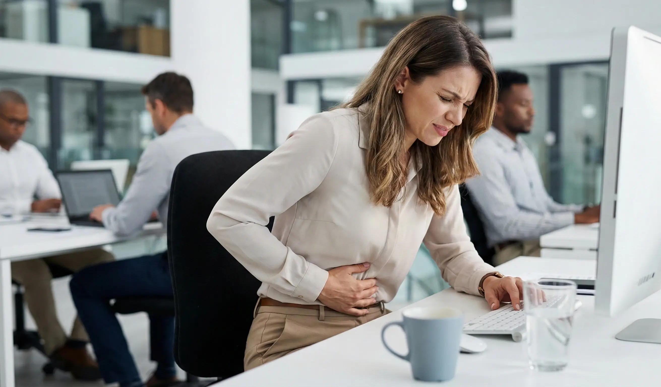 Femme au travail souffrant de douleurs abdominales liées à une cystite