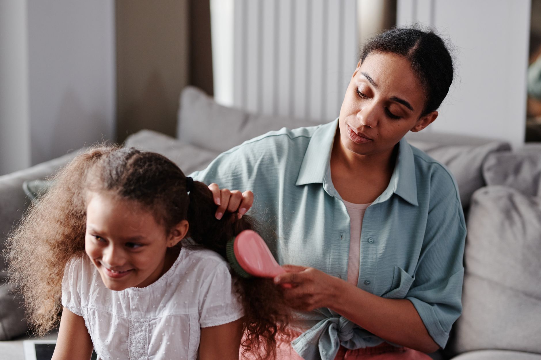 Mère peignant soigneusement les cheveux de sa fille