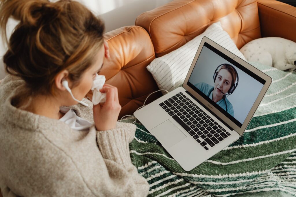 Adulte malade en téléconsultation avec un médecin depuis son canapé